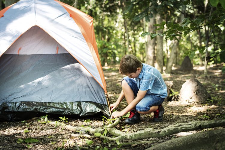 A boy putting up his tent.